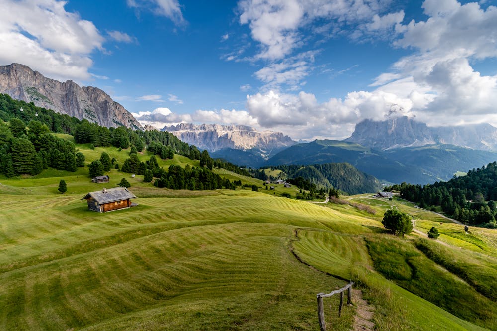 Man sieht eine herrliche Almlandschaft. Grüner Weiden mit einer Berghütte